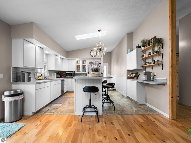 431 E Bittner Ave, Reed City, MI 49618 - kitchen with open shelves, a breakfast bar, stainless steel appliances, white cabinetry, and light wood-type flooring