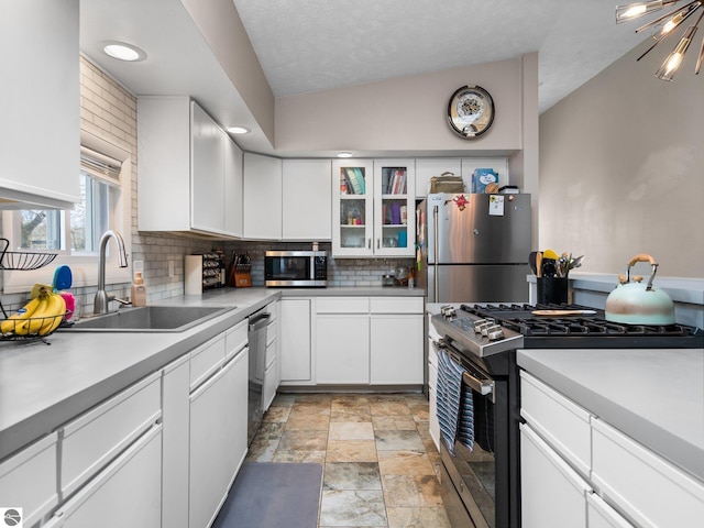 431 E Bittner Ave, Reed City, MI 49618 - kitchen featuring a sink, stainless steel appliances, white cabinetry, stone finish flooring, and tasteful backsplash