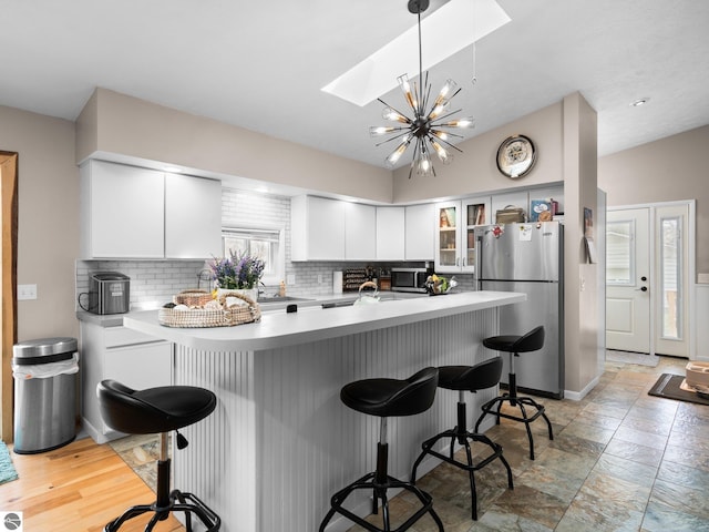 431 E Bittner Ave, Reed City, MI 49618 - kitchen with a kitchen breakfast bar, a skylight, tasteful backsplash, glass insert cabinets, and stainless steel appliances