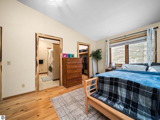 431 E Bittner Ave, Reed City, MI 49618 - bedroom featuring a walk in closet, vaulted ceiling, a closet, ensuite bathroom, and light wood-style flooring