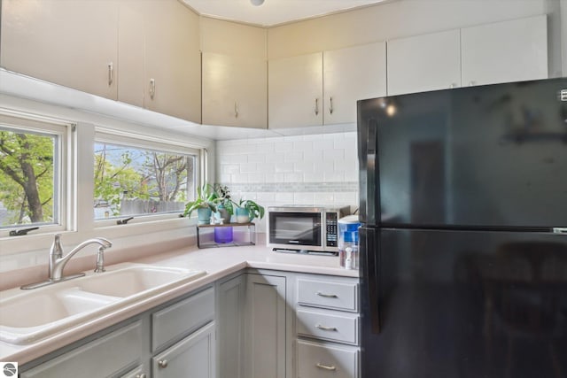 422 W Center, Alma, MI 48801 - kitchen with tasteful backsplash, a sink, light countertops, freestanding refrigerator, and stainless steel microwave