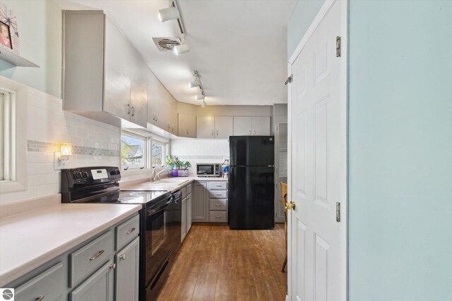 422 W Center, Alma, MI 48801 - kitchen featuring light countertops, black appliances, decorative backsplash, gray cabinetry, and hardwood / wood-style flooring