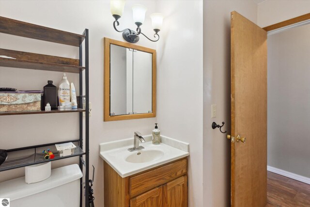 422 W Center, Alma, MI 48801 - half bathroom with vanity, wood finished floors, a chandelier, and toilet