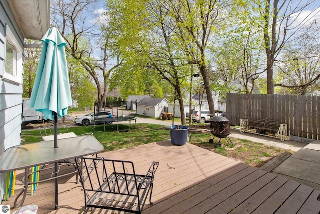 422 W Center, Alma, MI 48801 - wooden deck with a trampoline, fence, an outdoor structure, a yard, and outdoor dining space