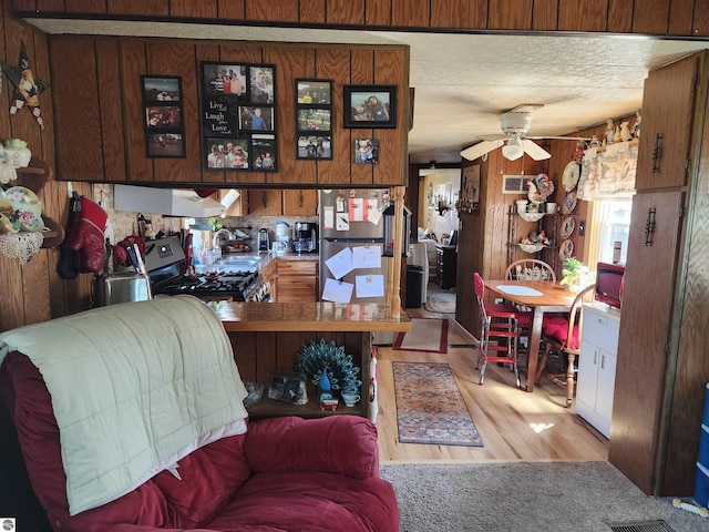 living room featuring wooden walls, ceiling fan, and wood finished floors