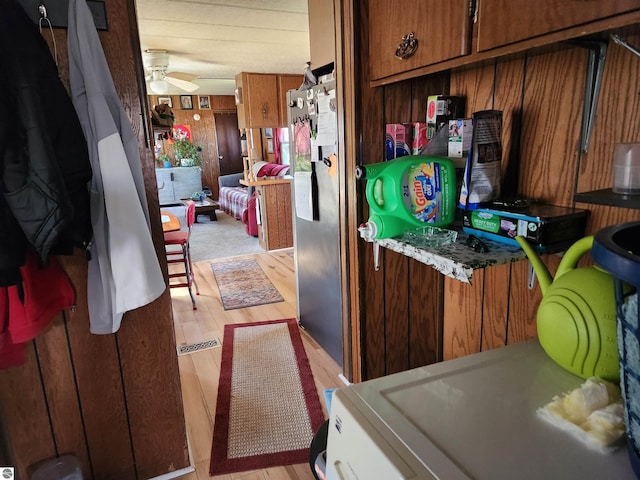 kitchen with light wood-type flooring, a ceiling fan, and brown cabinets