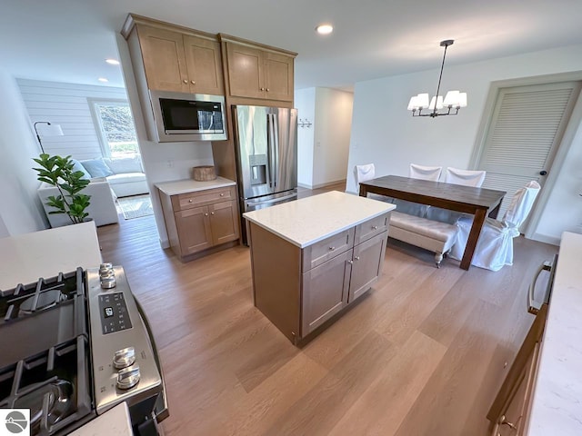kitchen featuring decorative light fixtures, light wood-type flooring, light countertops, a notable chandelier, and stainless steel appliances