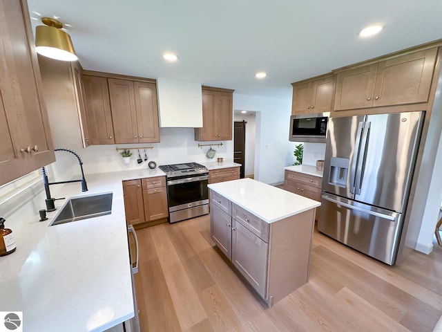 kitchen with a sink, a center island, stainless steel appliances, and light wood-style flooring