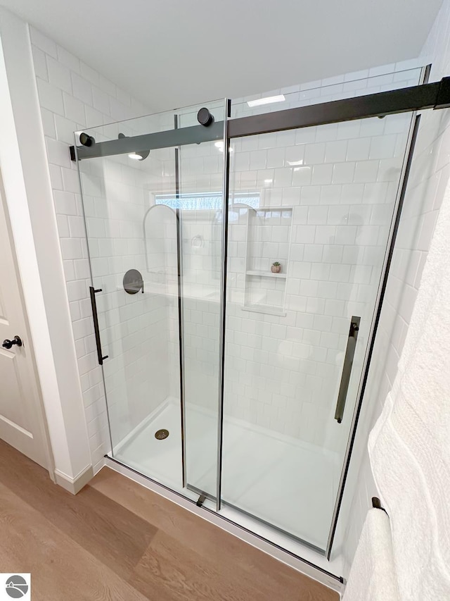full bathroom featuring a stall shower and wood finished floors