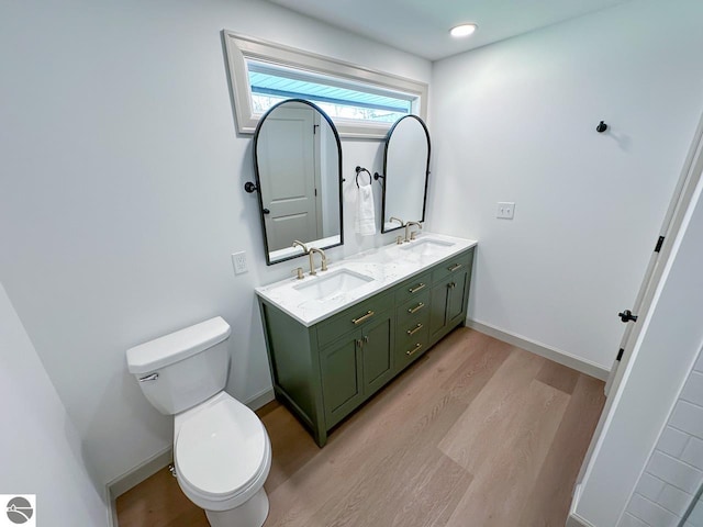 full bath featuring double vanity, a sink, wood finished floors, and toilet