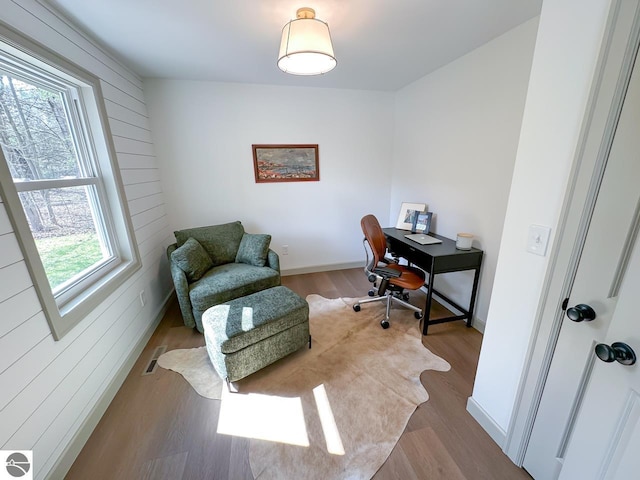 home office with baseboards, wood walls, wood finished floors, and visible vents