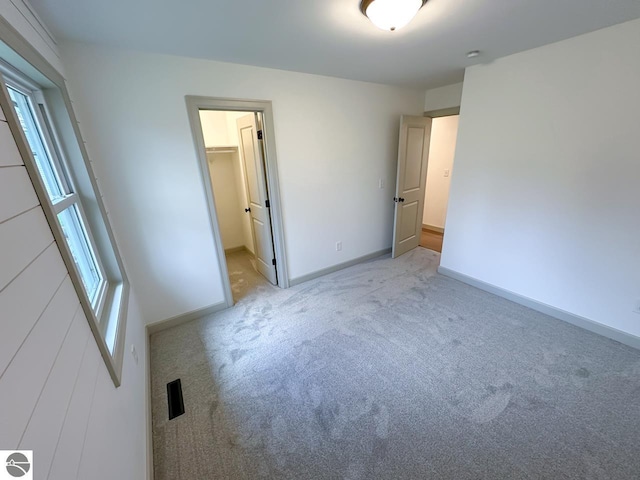 unfurnished bedroom with baseboards, carpet, a spacious closet, and a closet
