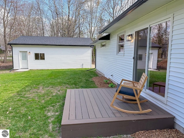 wooden deck featuring a lawn and an outbuilding
