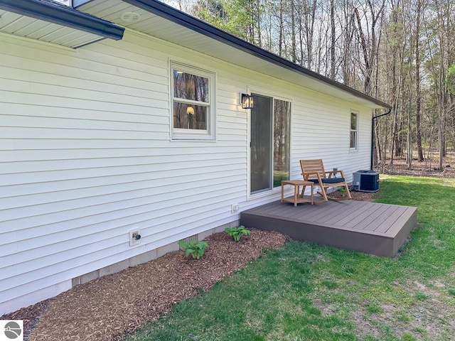 exterior space with a lawn, a deck, and cooling unit