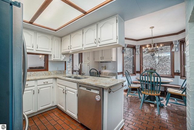 kitchen with a sink, brick floor, stainless steel appliances, and an inviting chandelier