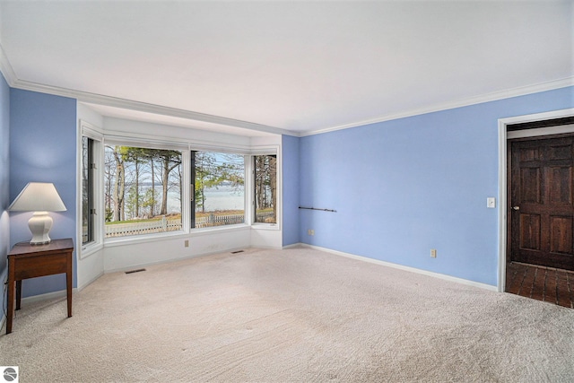 carpeted empty room featuring baseboards, ornamental molding, and visible vents