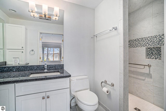 bathroom with toilet, tiled shower, and vanity