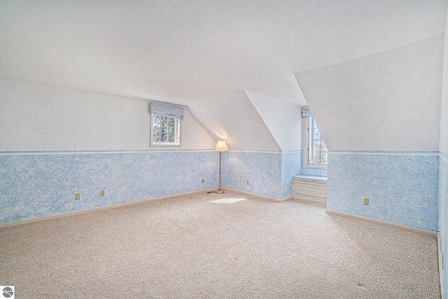 bonus room with plenty of natural light, carpet, vaulted ceiling, and wallpapered walls