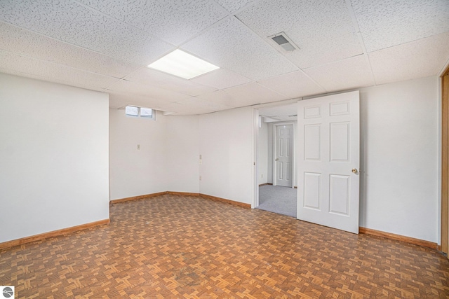 basement with baseboards, visible vents, and a drop ceiling