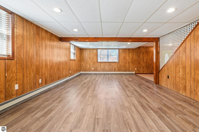 basement with baseboard heating, wood walls, wood finished floors, and a paneled ceiling