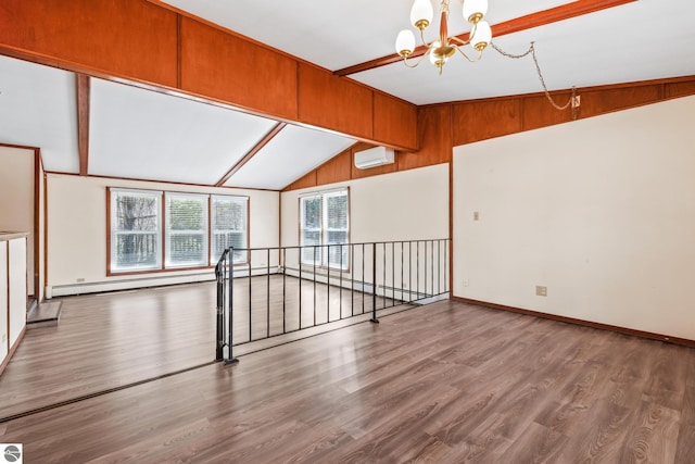spare room featuring wood finished floors, lofted ceiling, baseboards, a wall mounted AC, and a notable chandelier