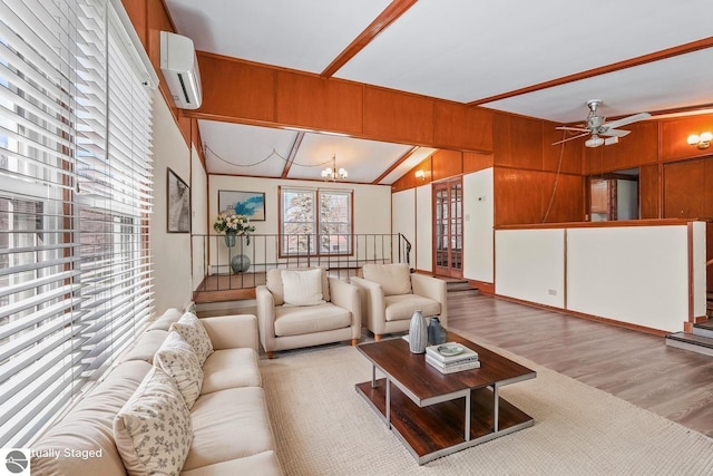 living area with a wall unit AC, wood finished floors, ceiling fan with notable chandelier, lofted ceiling, and wooden walls