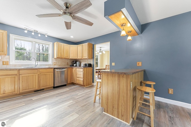 kitchen featuring a kitchen breakfast bar, tasteful backsplash, a sink, and dishwasher