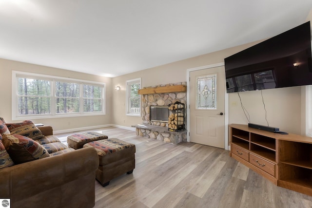 living area featuring baseboards, light wood finished floors, and a fireplace