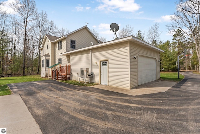 exterior space featuring an attached garage, ac unit, and aphalt driveway