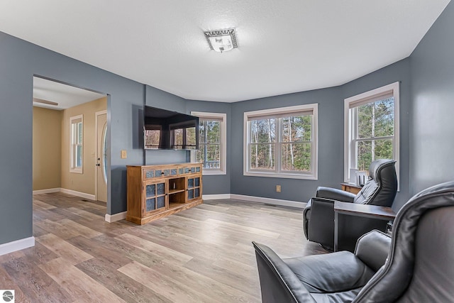 living area featuring baseboards and light wood-style flooring