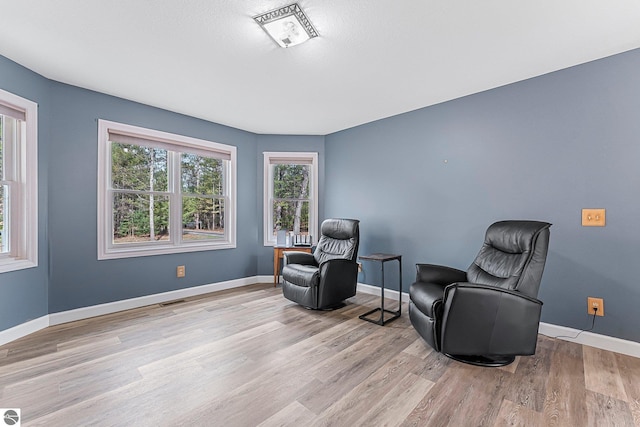 living area featuring baseboards, wood finished floors, and visible vents
