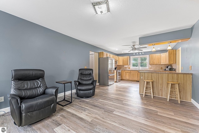 sitting room featuring light wood-style floors, baseboards, and ceiling fan