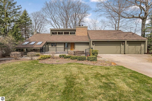 mid-century inspired home featuring a porch, a chimney, a front yard, a garage, and concrete driveway