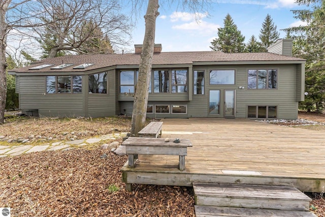 back of house with a wooden deck and a chimney
