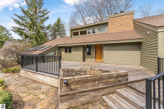 exterior space featuring roof with shingles, a chimney, and a deck