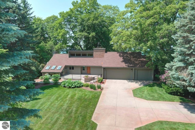 mid-century inspired home with concrete driveway, an attached garage, a chimney, and a front lawn