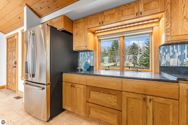 kitchen with stainless steel fridge, dark stone countertops, baseboards, and tasteful backsplash