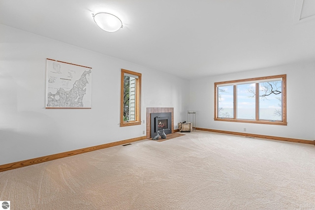 unfurnished living room with baseboards, visible vents, and light carpet