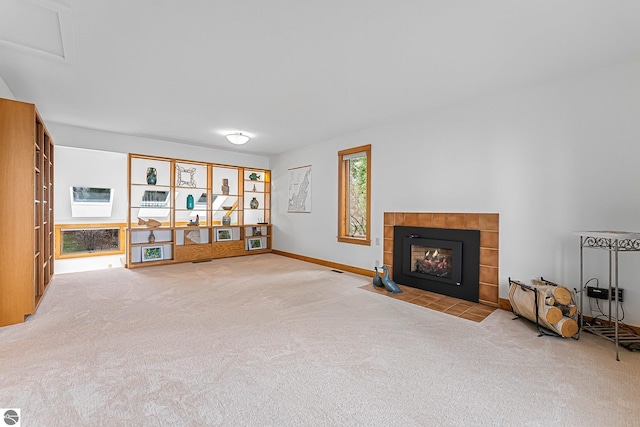 carpeted living room featuring baseboards and a tile fireplace