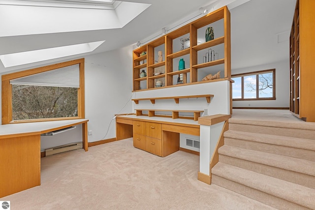 unfurnished office with light carpet, built in desk, baseboards, a baseboard radiator, and a skylight