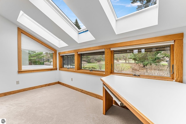 unfurnished office with baseboards, carpet flooring, and lofted ceiling with skylight