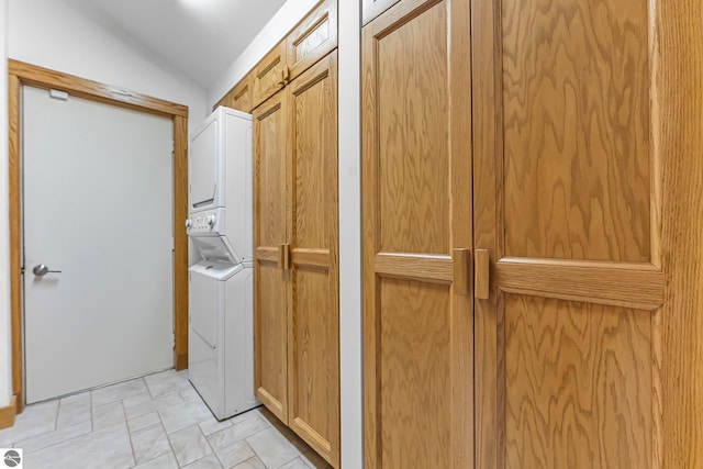 washroom with stacked washer and clothes dryer and cabinet space