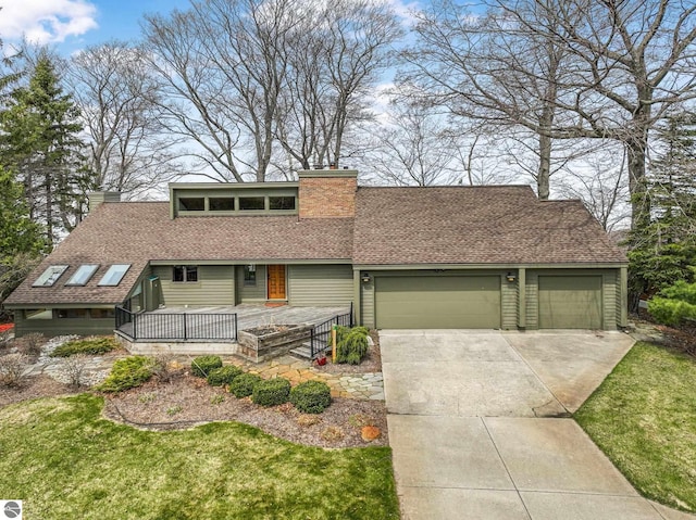 mid-century inspired home featuring a garage, a front yard, roof with shingles, a chimney, and concrete driveway