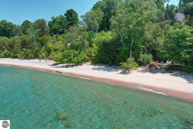 exterior space featuring a view of the beach, a water view, and a forest view
