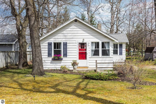 bungalow-style home featuring fence, a chimney, and a front lawn