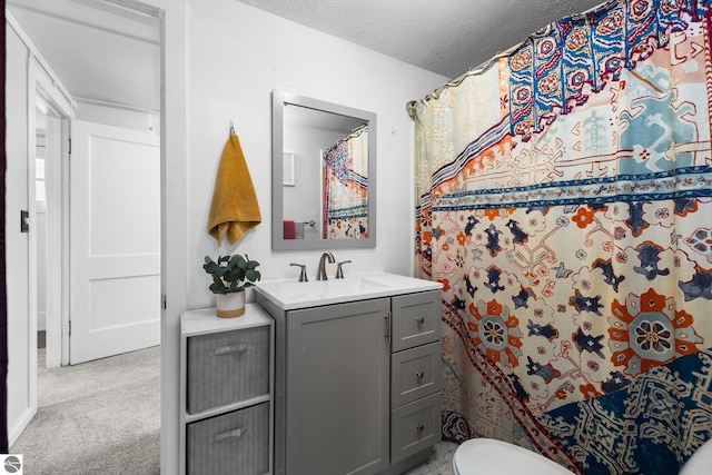 bathroom featuring toilet, a textured ceiling, and vanity