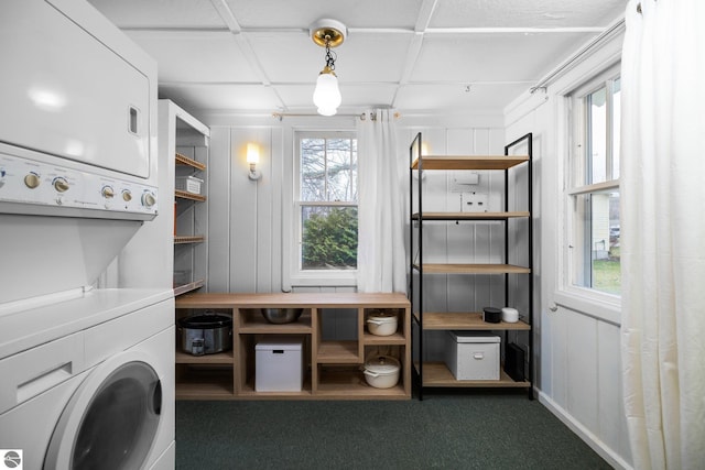 clothes washing area with carpet, stacked washer and dryer, and laundry area