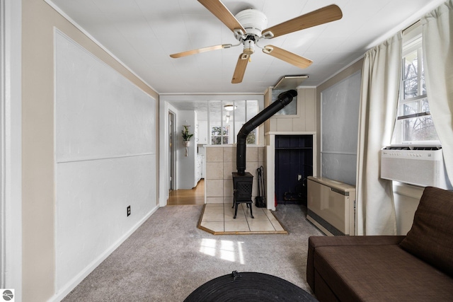 living area featuring a wood stove, a ceiling fan, cooling unit, and carpet flooring