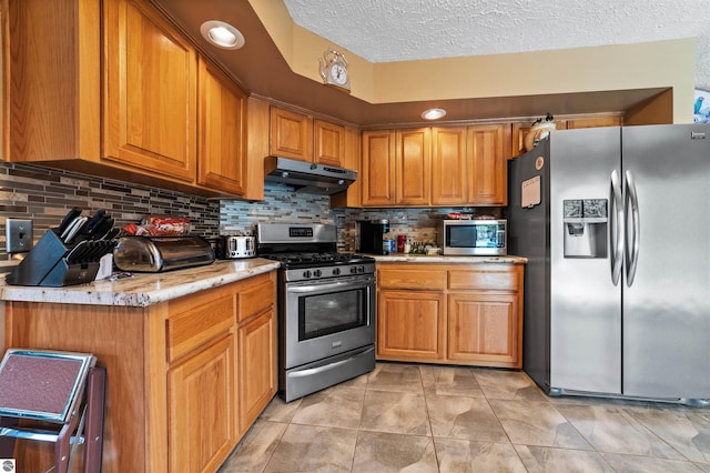 kitchen featuring brown cabinetry, appliances with stainless steel finishes, and under cabinet range hood