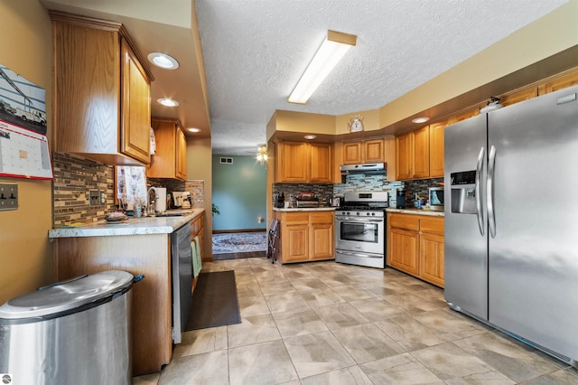 kitchen with light countertops, decorative backsplash, appliances with stainless steel finishes, and under cabinet range hood